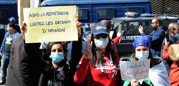 Des manifestant·e·s sont rassemblé·e·s et tiennent une pancarte écrite en français : «A bas la repression liberez les detenus d'opinion» et une autre en arabe.