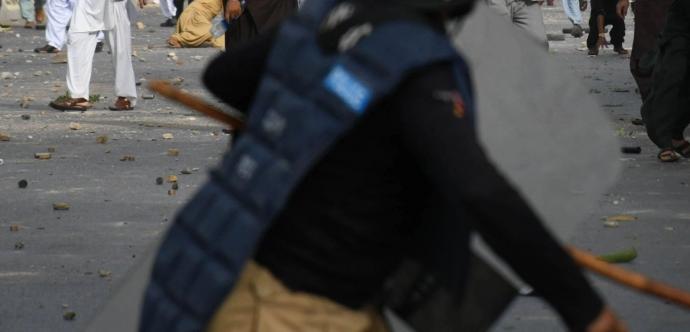 policier avec un baton à une manifestation au Pakistan