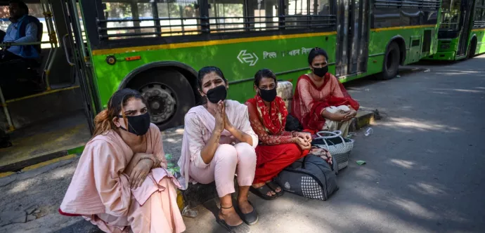 Des femmes avec un masque devant un autobus 