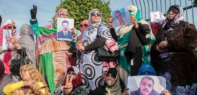 Des personnes qui manifestent avec des photos des personnes incarcérées. 