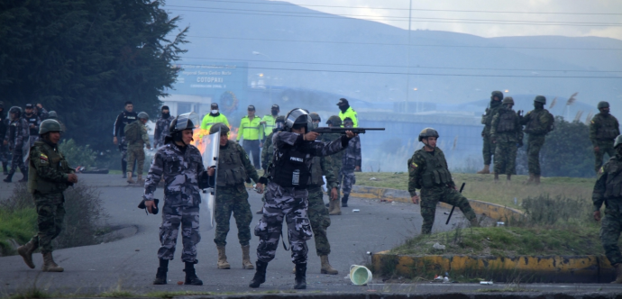 Des militaires et la police avec un militaire qui pointe son arme