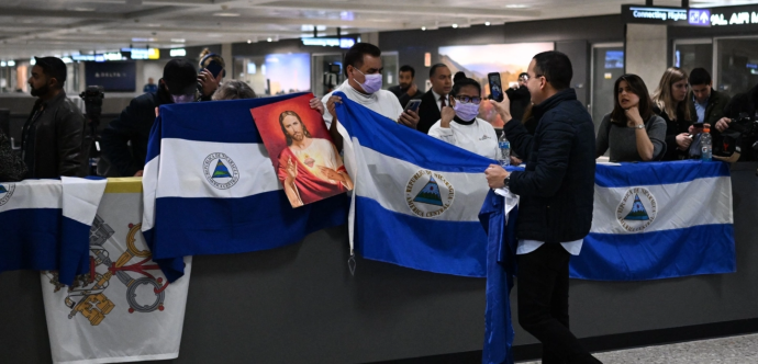 Des personnes qui attendent dans un aéroport avec des drapeaux du Nicaragua