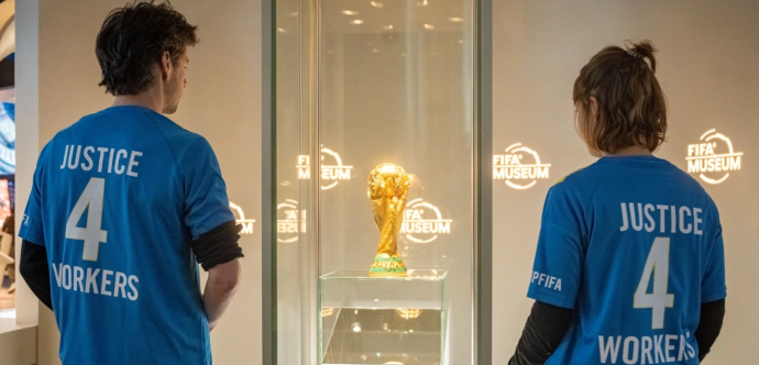 Travailleurs des droits humains regardant le trophée de la coupe du monde FIFA installé dans une vitrine