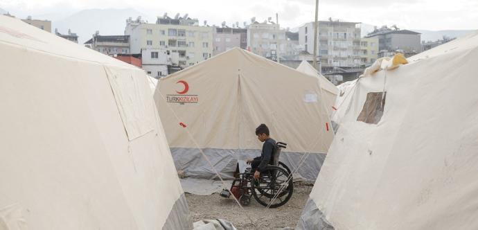 personne en situation de handicap en fauteuil roulant entre des tentes de campement