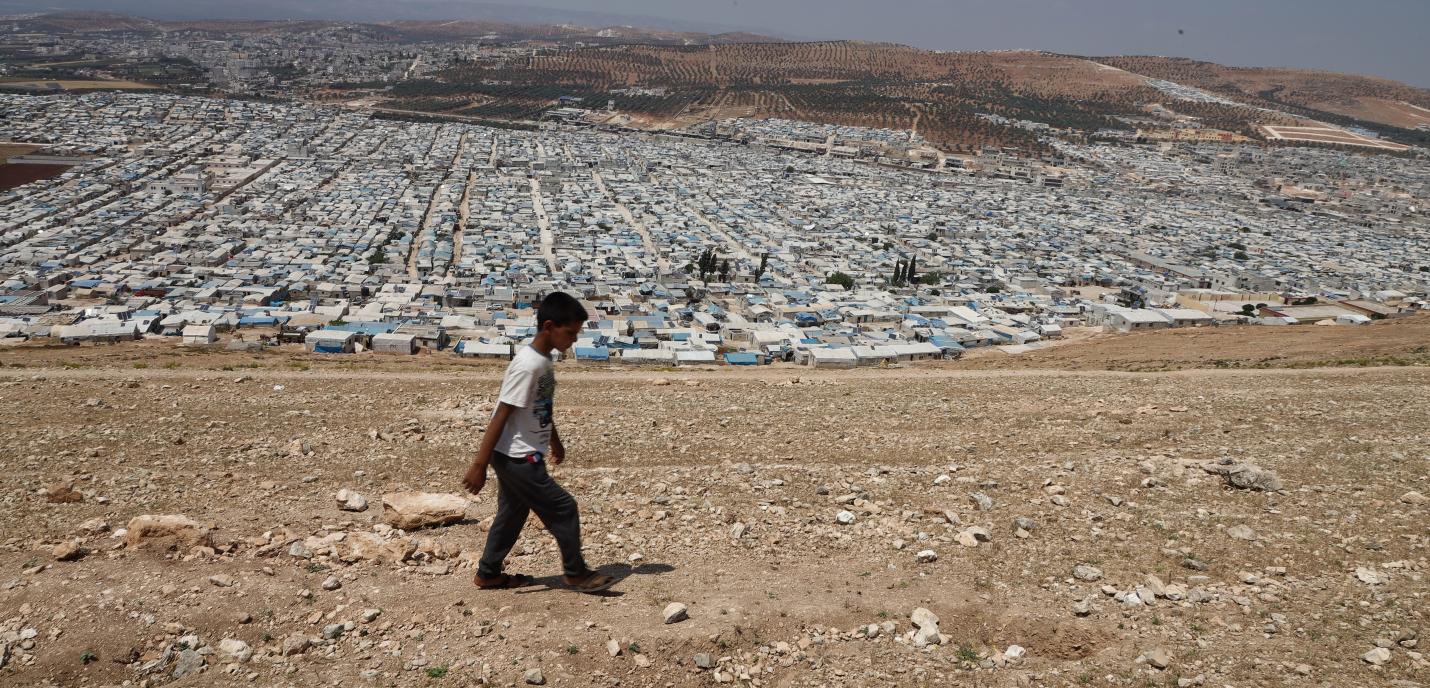 Un garçon marche devant des campements située au nord d'Idlib.