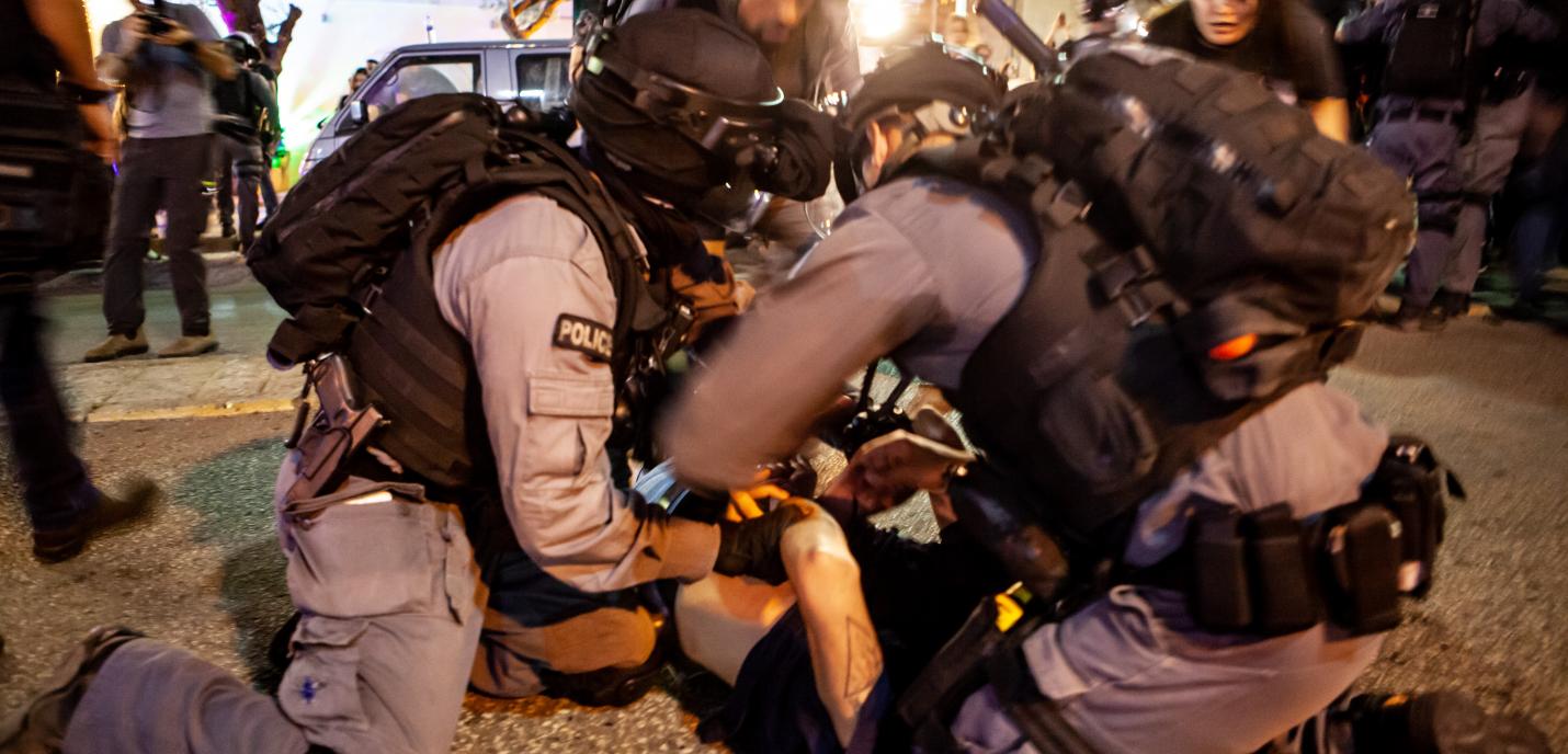 Trois policiers israéliens immobilisent un citoyen palestinien à Haifa lors d'une manifestation le 9 mai 2021.