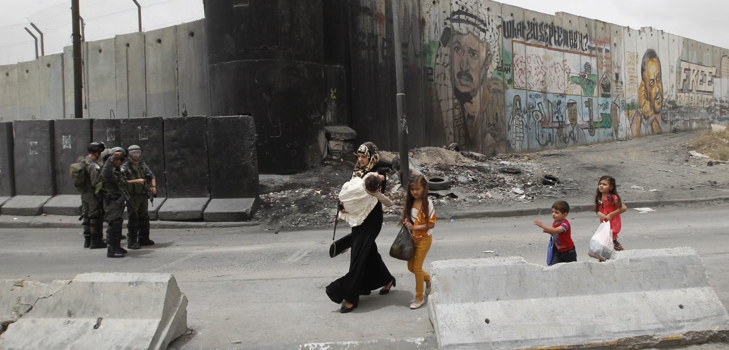 Une femme et des enfants palestiniens s’apprêtent à traverser le point de passage de Qalandiya, qui relie Ramallah à Jérusalem-Est, toutes deux situées en Cisjordanie occupée, afin de rejoindre le site de la mosquée d'Al Aqsa, à Jérusalem-Est, pour les premières prières du vendredi du ramadan, mois sacré pour les musulmans, le 2 juin 2017