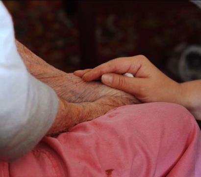Une main est déposée sur le bras d'une personne âgée