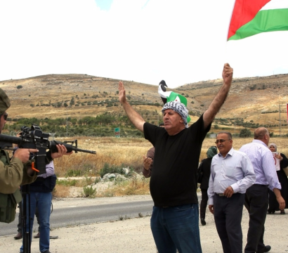 Des palestiniens avec drapeaux devant des militaires armés