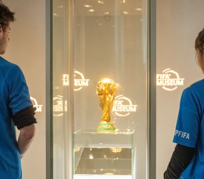 Travailleurs des droits humains regardant le trophée de la coupe du monde FIFA installé dans une vitrine