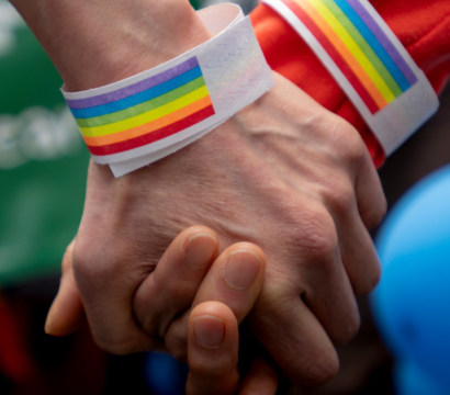 Deux mains se tenant l'une l'autre avec des bracelets arc-en-ciel.