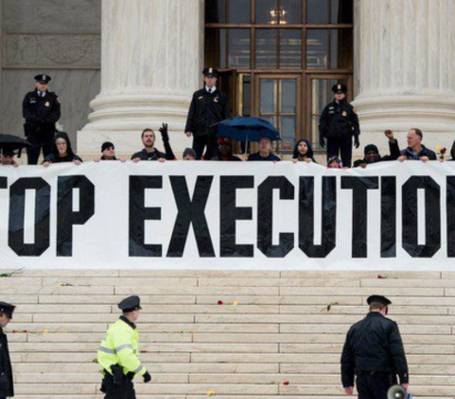 Des manifestants tiennent une banderole "Stop Executions" devant un grand bâtiment